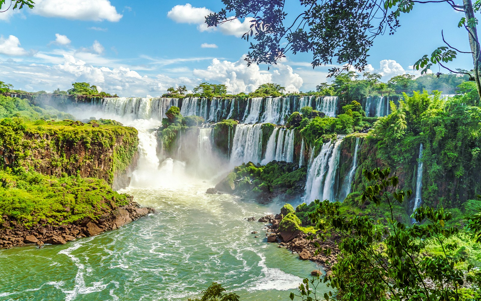 Iguazu Falls cascading over lush cliffs in Argentinian National Park.