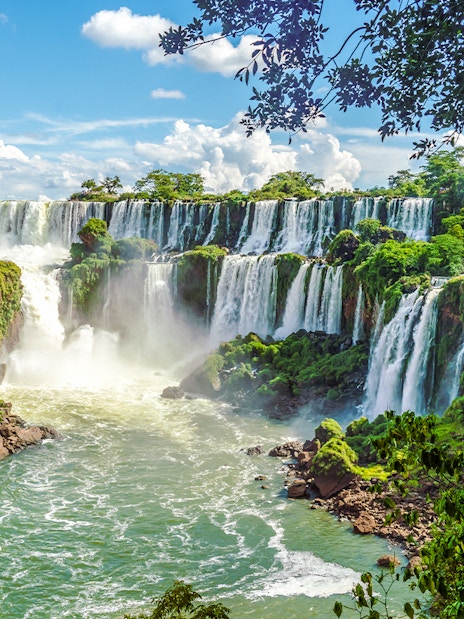 Iguazu Falls cascading over lush cliffs in Argentinian National Park.