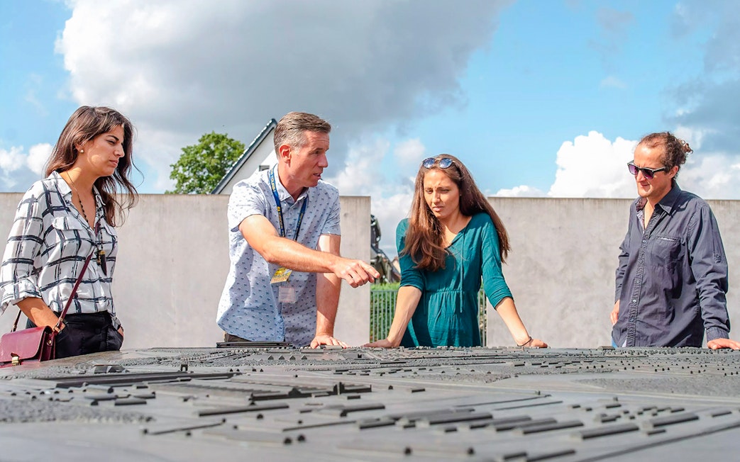 Guests with a guide at Sachsenhausen Concentration Camp Memorial examining a site model.