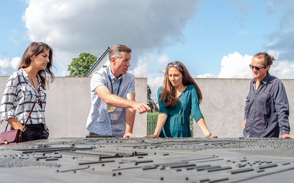 Guests with a guide at Sachsenhausen Concentration Camp Memorial examining a site model.