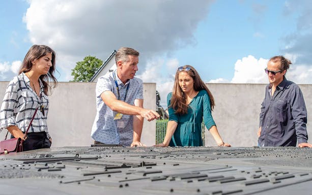 Guests with a guide at Sachsenhausen Concentration Camp Memorial examining a site model.