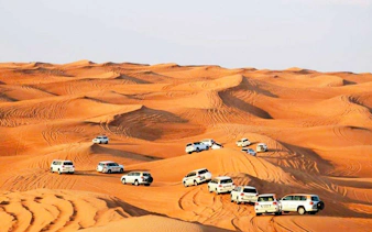 Convoy of SUVs driving over sand dunes during Dubai Desert Safari.