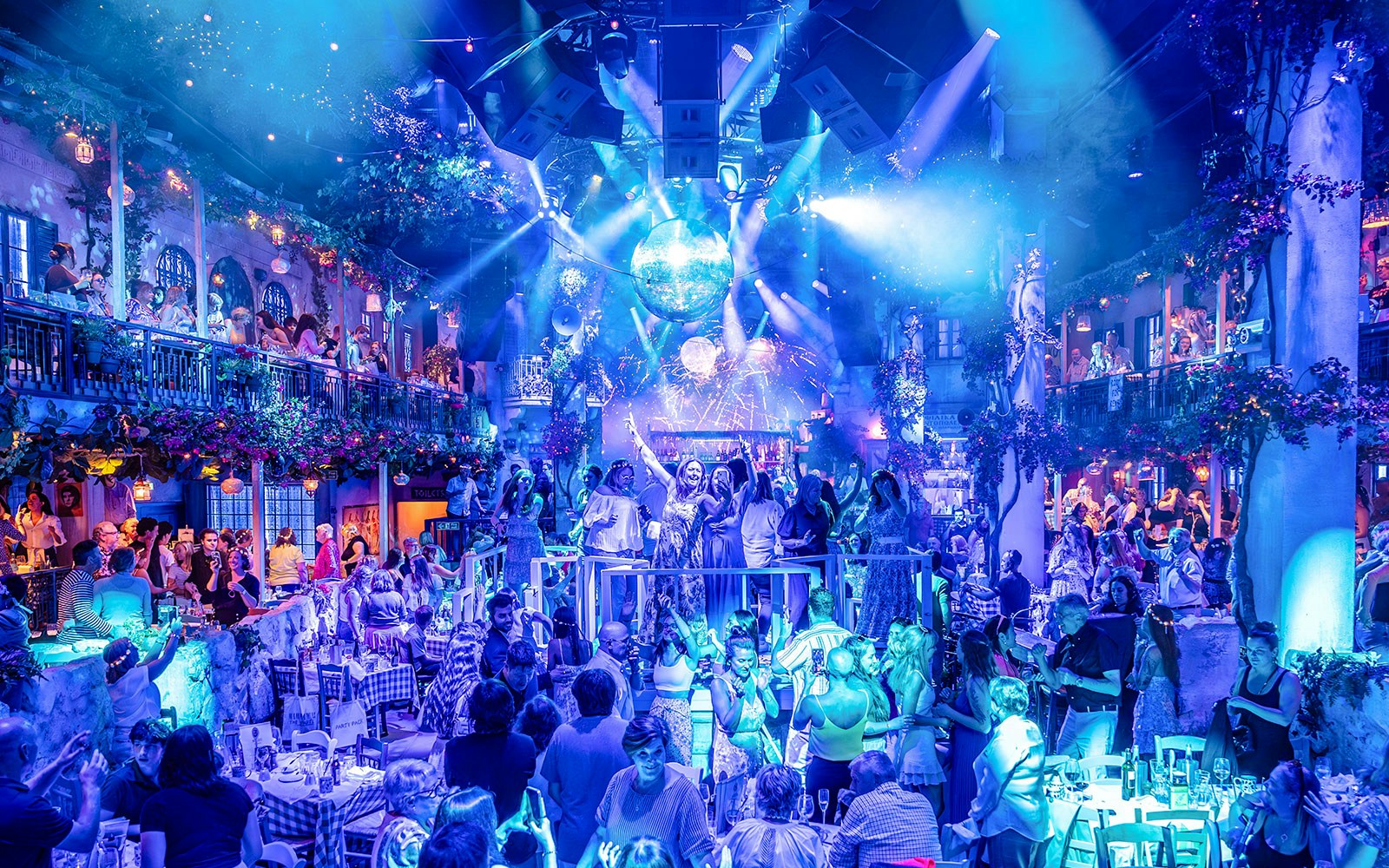 Guests enjoying Mamma Mia! The Party with vibrant lights and lively atmosphere.