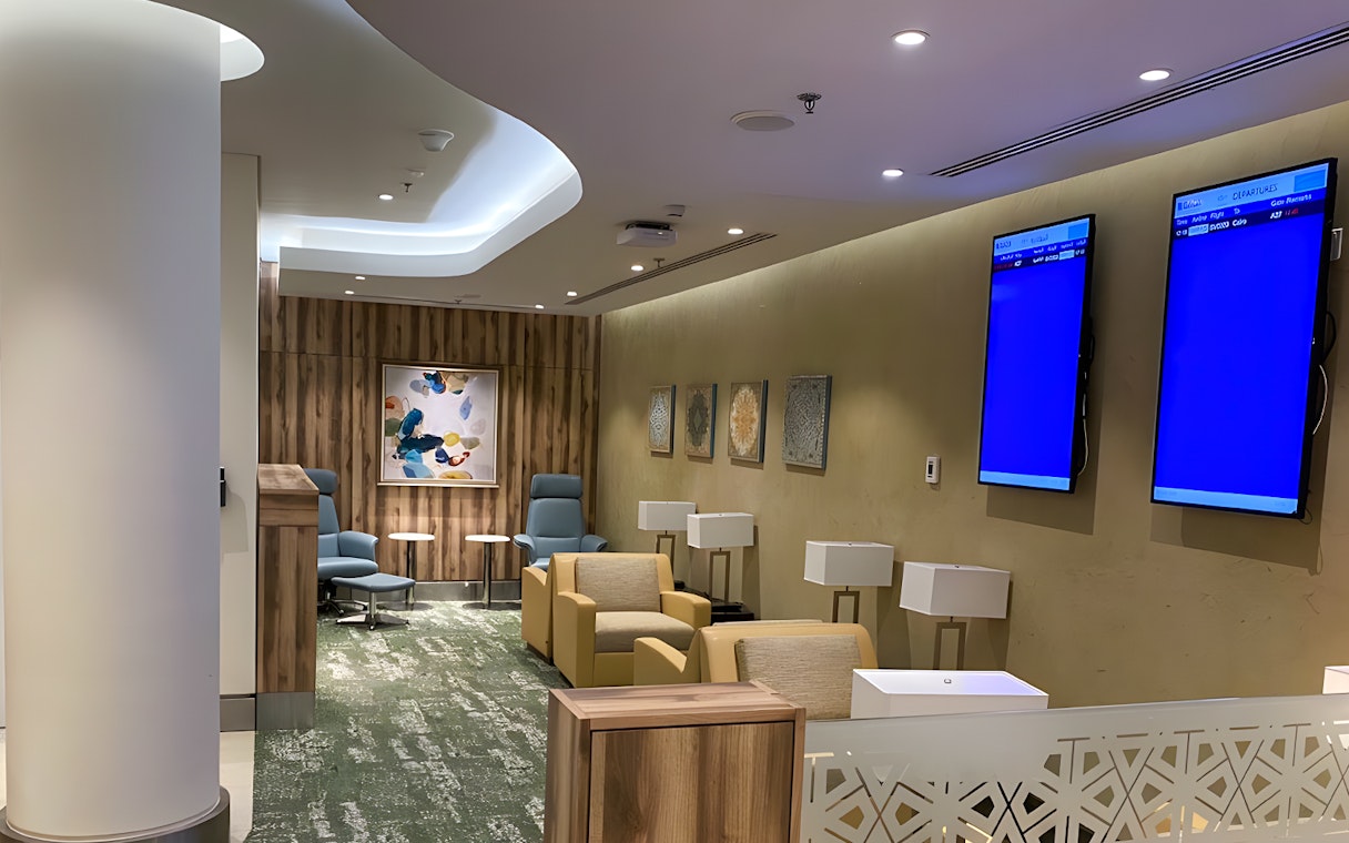 Premium lounge seating area at Jeddah Airport with modern decor and flight information screens.