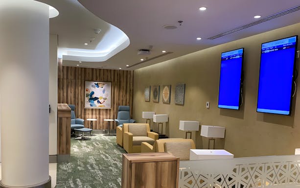 Premium lounge seating area at Jeddah Airport with modern decor and flight information screens.