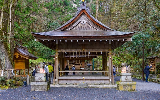 Kifune Shrine in Kyoto, Japan with visitors exploring the wooden pavilion surrounded by forest.