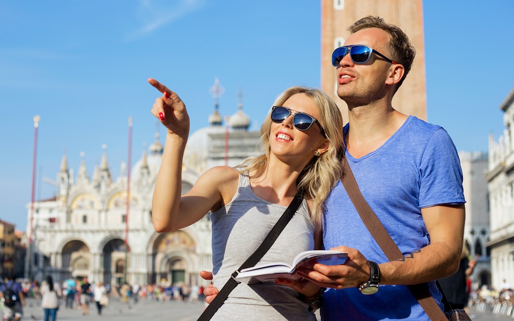 Tourists exploring St. Mark’s Basilica in Venice with a guidebook.