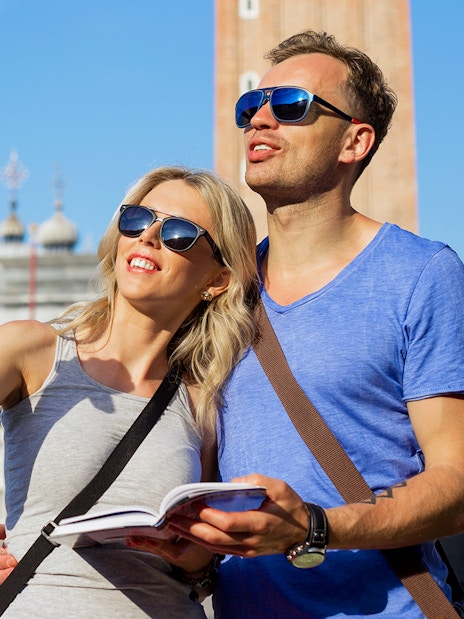 Tourists exploring St. Mark’s Basilica in Venice with a guidebook.