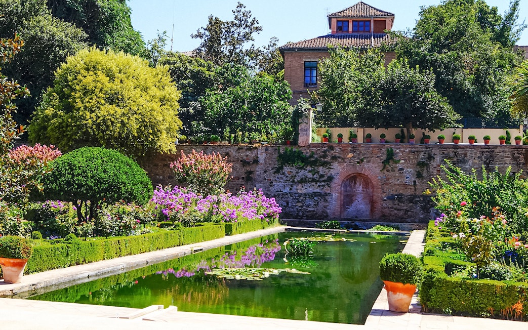 Generalife Gardens with lush greenery and reflective pool, part of Alhambra complex in Granada, Spain.