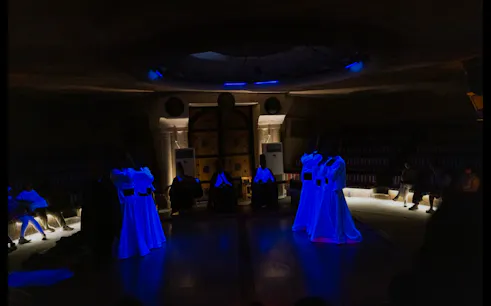Whirling Dervishes performing Sema ceremony in a dimly lit cave, Cappadocia.
