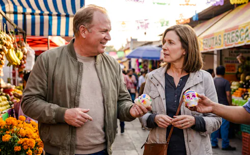 Couple holding Day of the Dead skulls at Oaxaca market during walking tour.