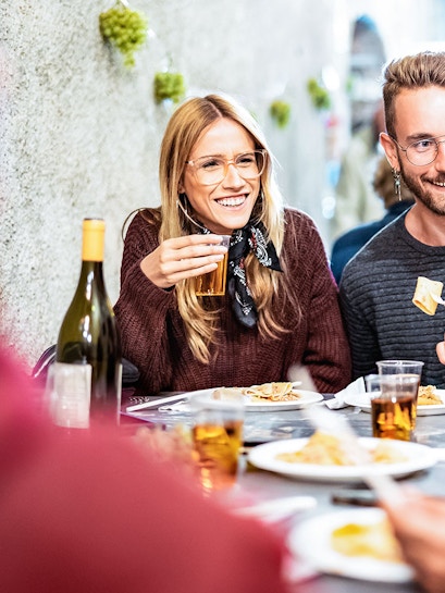Group enjoying a meal at an outdoor restaurant in a lively city setting.