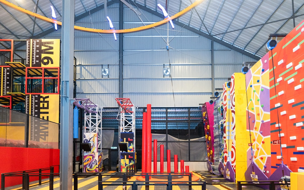 Indoor adventure hub with climbing walls and obstacle course.