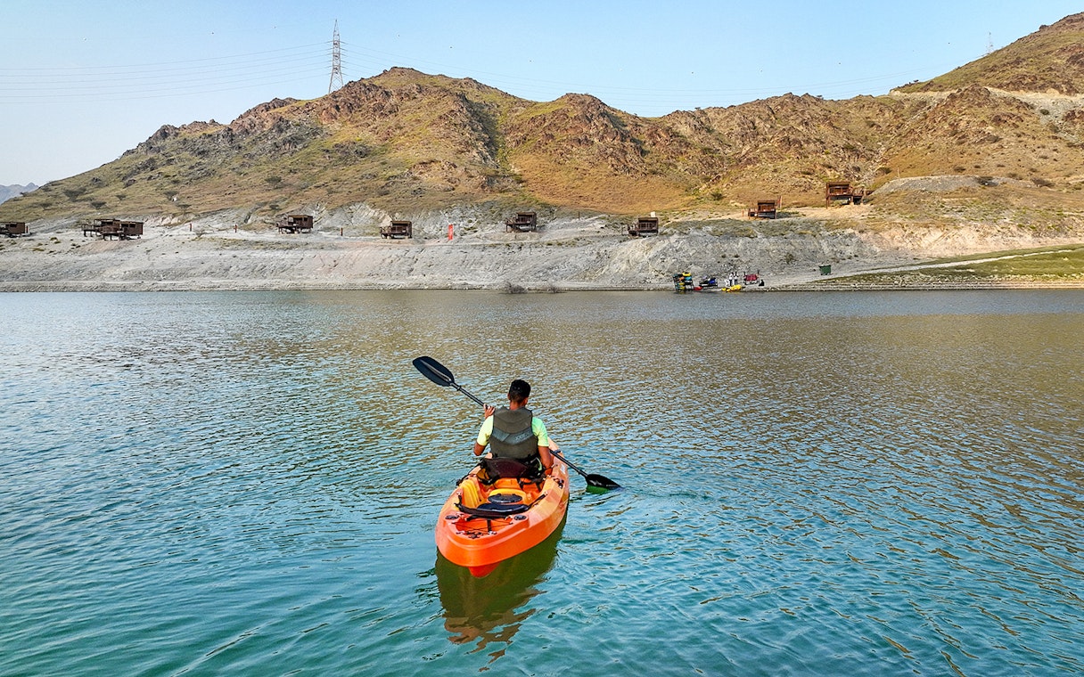 Kayaker paddling on a lake with mountainous backdrop at Fujairah Adventure Park.