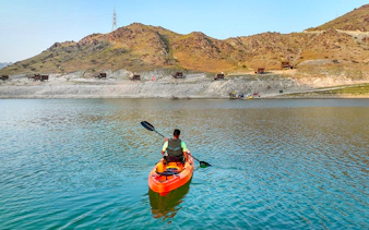 Kayaker paddling on a lake with mountainous backdrop at Fujairah Adventure Park.