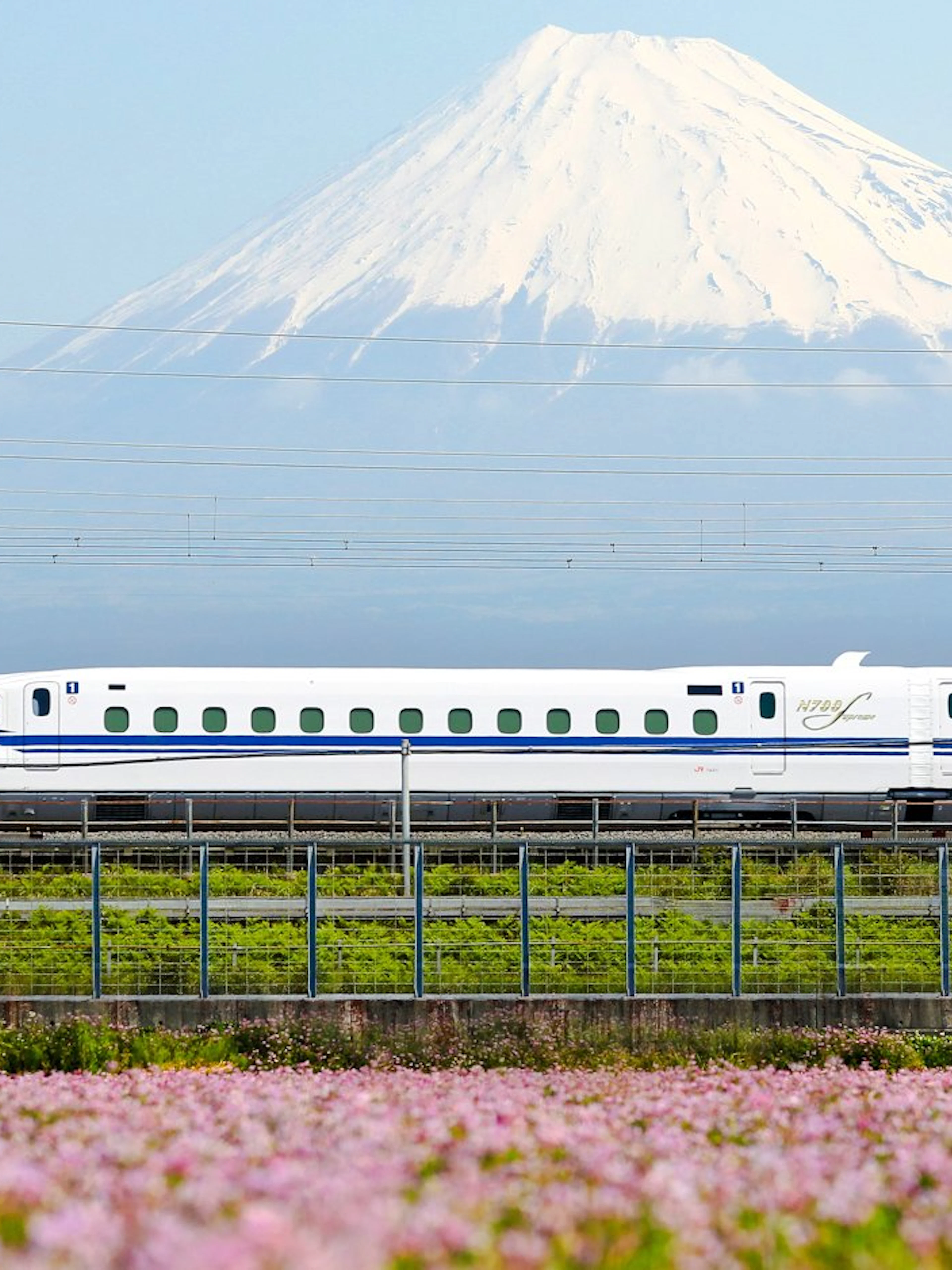 Shinkansen train passing with Mount Fuji in the background.