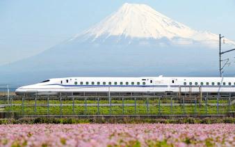 Shinkansen train passing with Mount Fuji in the background.