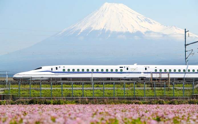 Shinkansen train passing with Mount Fuji in the background.