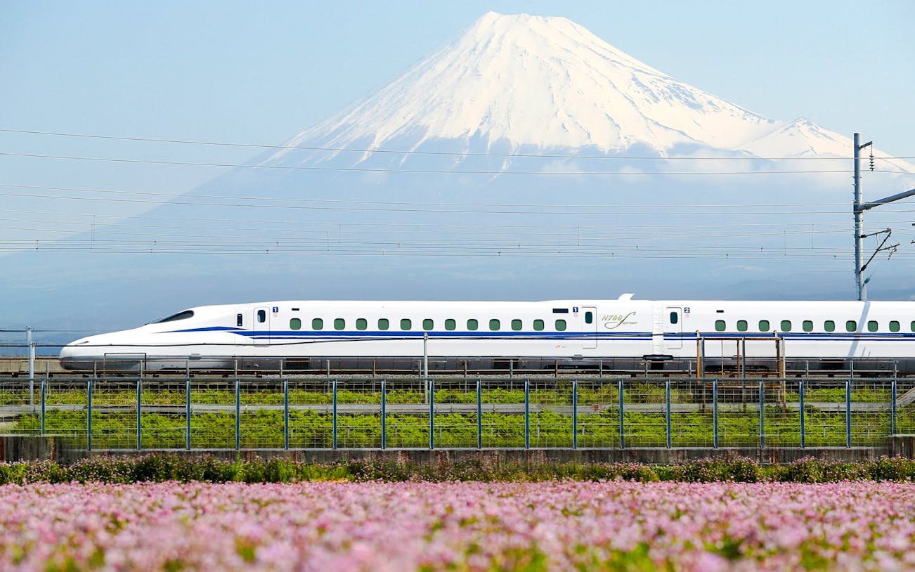 Shinkansen train passing with Mount Fuji in the background.