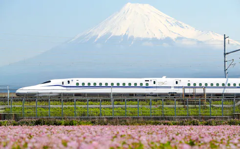 Shinkansen train passing with Mount Fuji in the background.