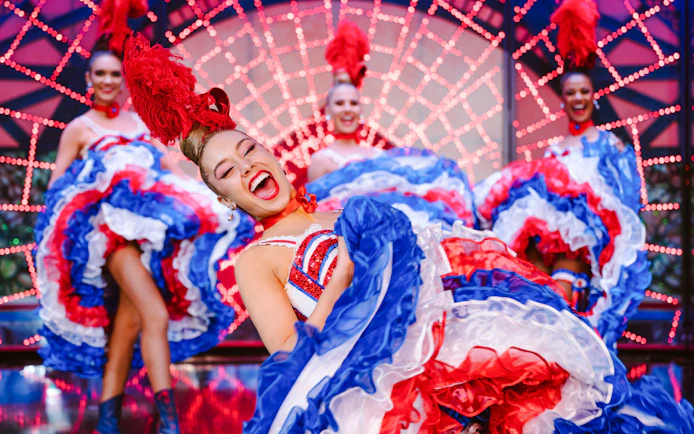 Dancers performing at the Moulin Rouge show in Paris with vibrant costumes.