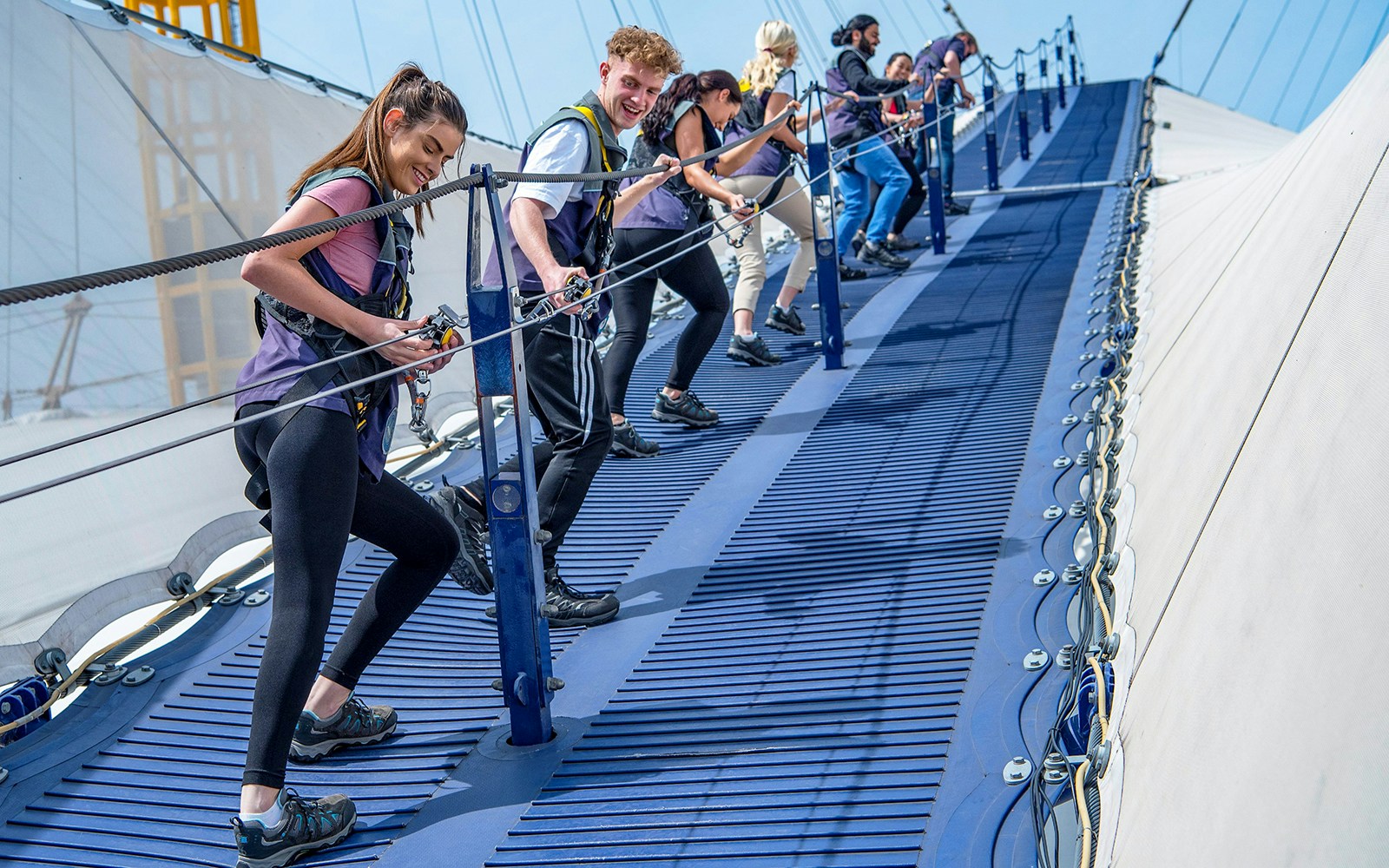 Group climbing the O2 Arena roof in London with safety gear.