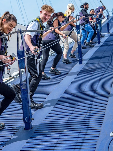 Group climbing the O2 Arena roof in London with safety gear.