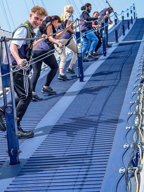 Group climbing the O2 Arena roof in London with safety gear.
