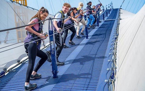 Group climbing the O2 Arena roof in London with safety gear.
