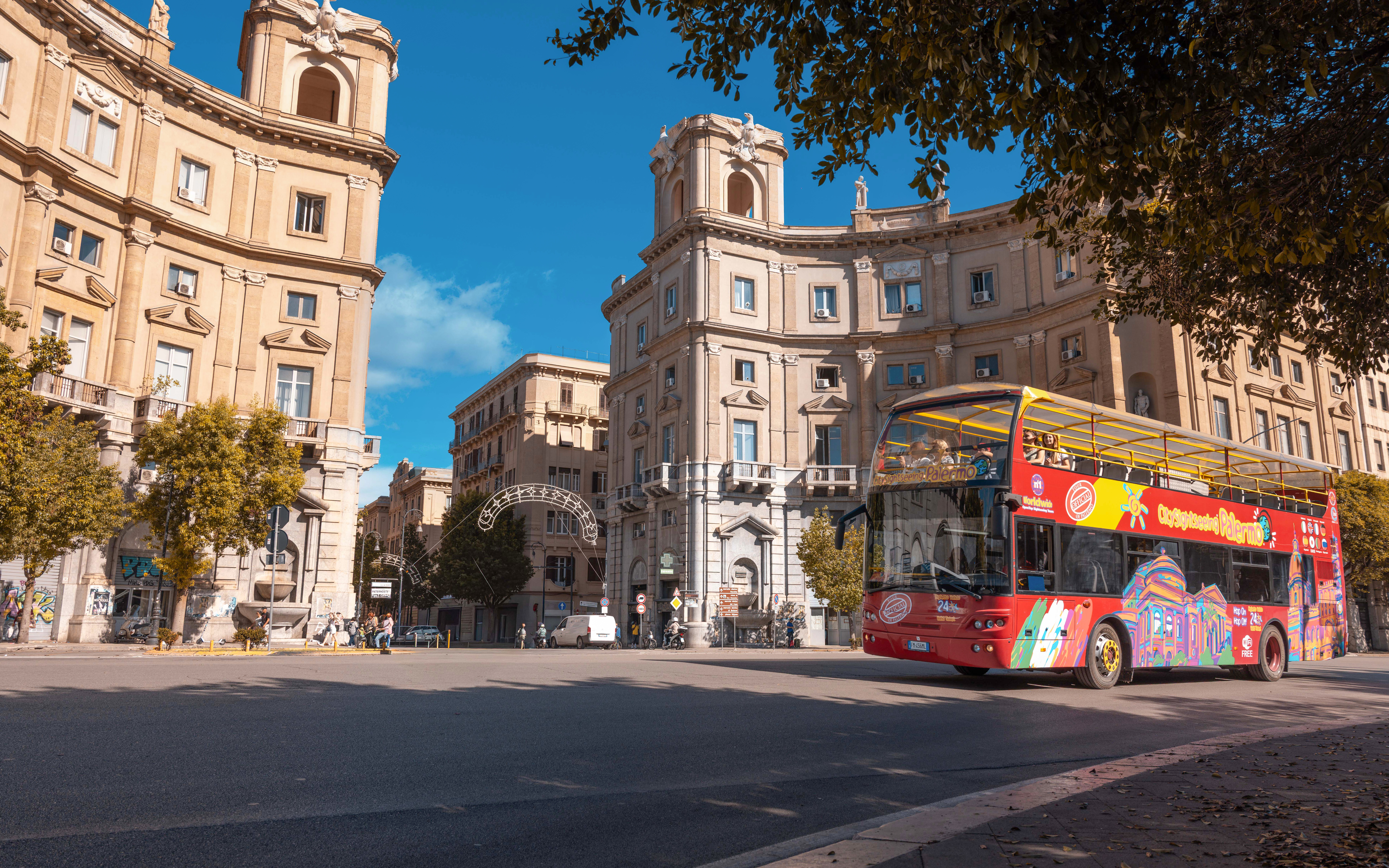 City Sightseeing bus in Palermo passing historic buildings.