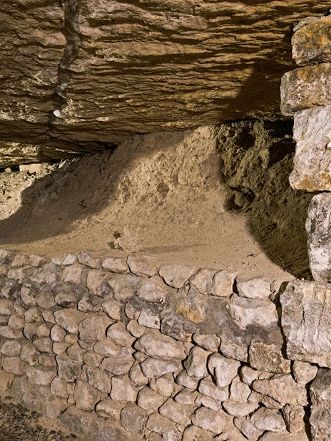 Underground stone passage in the Paris Catacombs with ancient support structures.