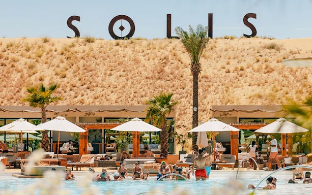 People enjoying a poolside experience at Terra Solis with desert backdrop.