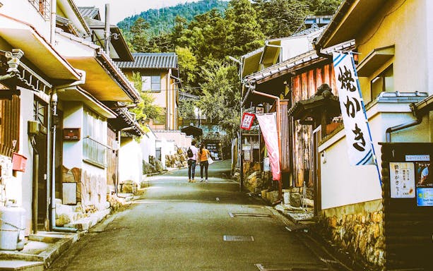 Street view of traditional buildings on Miyajima Island, Japan, with two people walking.