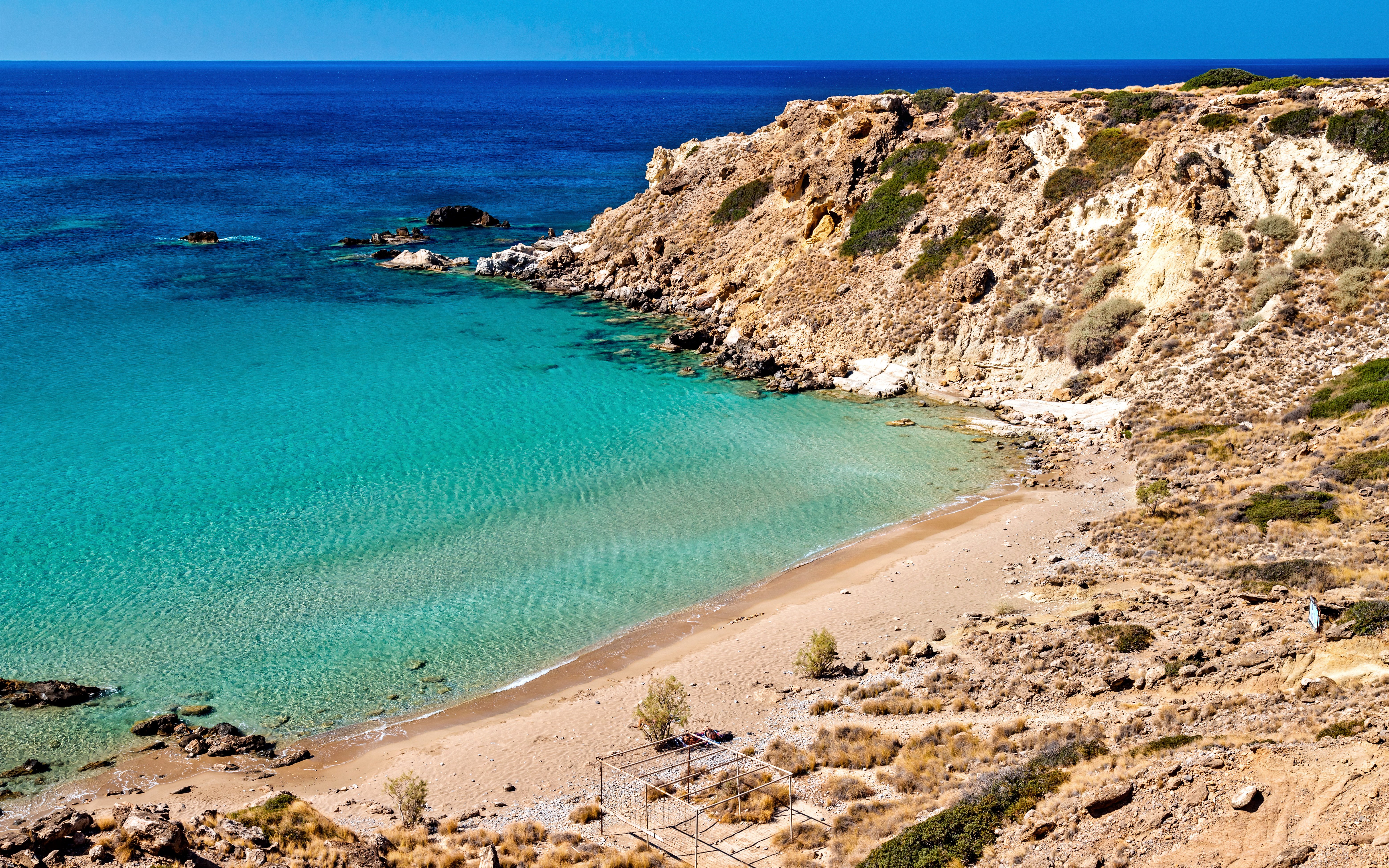 Ammoudi Beach in Greece with clear turquoise waters and rocky cliffs.