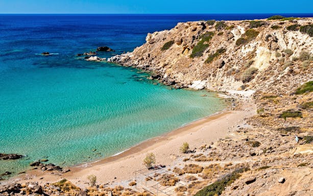 Ammoudi Beach in Greece with clear turquoise waters and rocky cliffs.