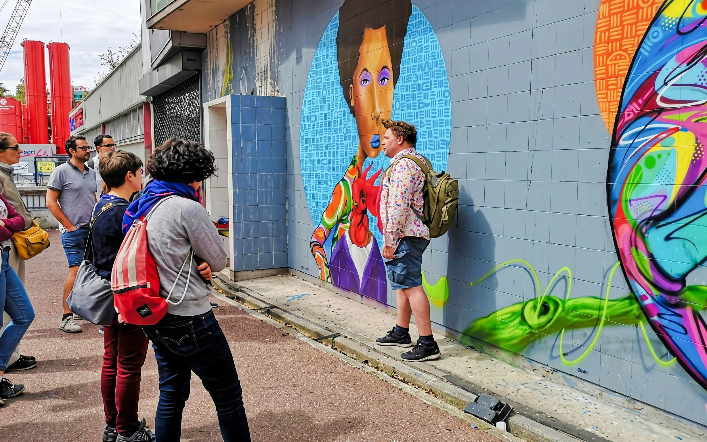 Tour group observing vibrant street art mural in Montmartre with local artist guide.