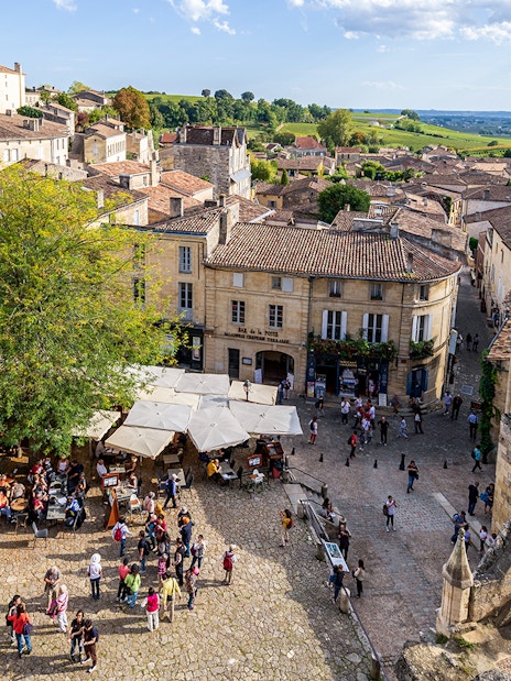 Saint-Emilion village square with outdoor café and historic architecture.