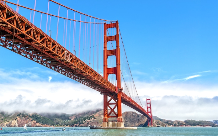 Golden Gate Bridge view from a ferry in San Francisco with hills in the background.