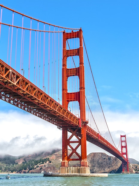 Golden Gate Bridge view from a ferry in San Francisco with hills in the background.