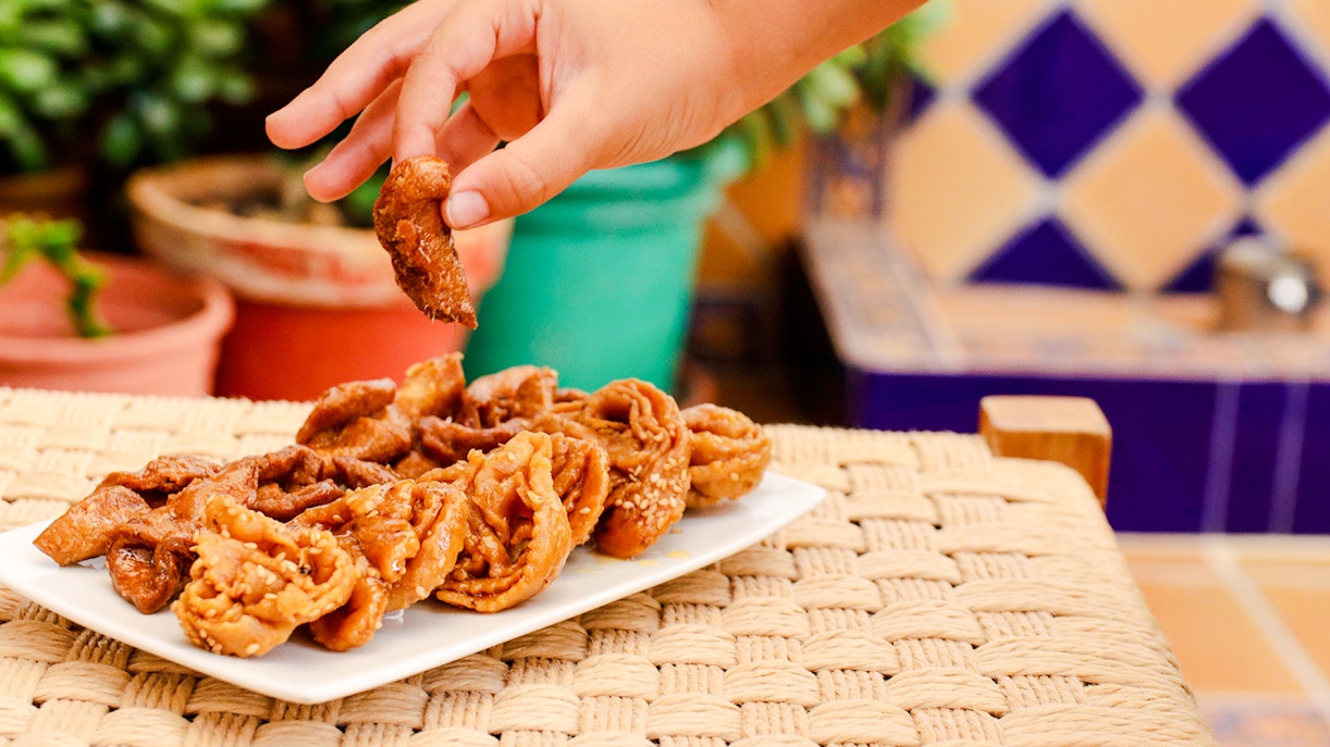 Hand picking Moroccan snacks from a plate at Jardin Secret.