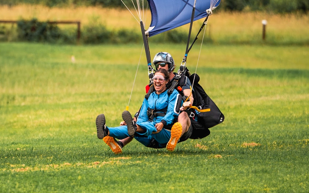 Tandem skydive landing in Sydney with grassy field backdrop.