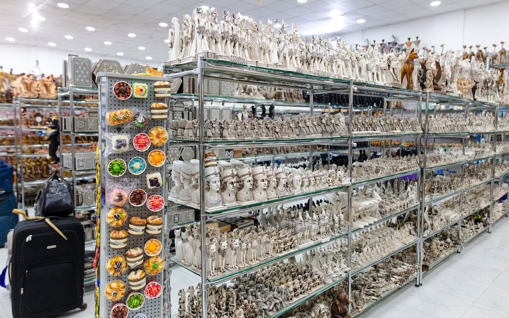 Ancient Egyptian statues and souvenirs displayed on shelves at the Grand Egyptian Museum.