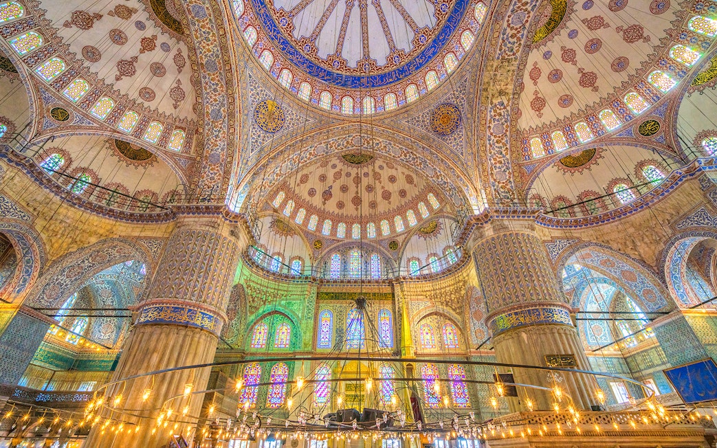 Interior of the Blue Mosque in Istanbul, showcasing intricate tilework and stained glass windows.
