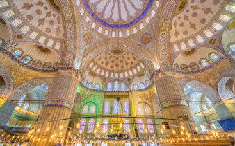 Interior of the Blue Mosque in Istanbul, showcasing intricate tilework and stained glass windows.