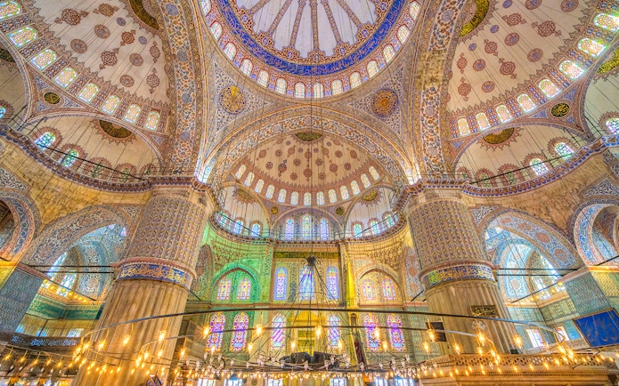 Interior of the Blue Mosque in Istanbul, showcasing intricate tilework and stained glass windows.