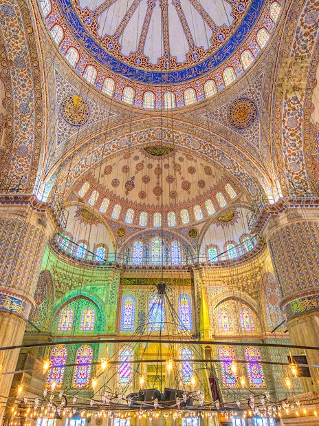 Interior of the Blue Mosque in Istanbul, showcasing intricate tilework and stained glass windows.