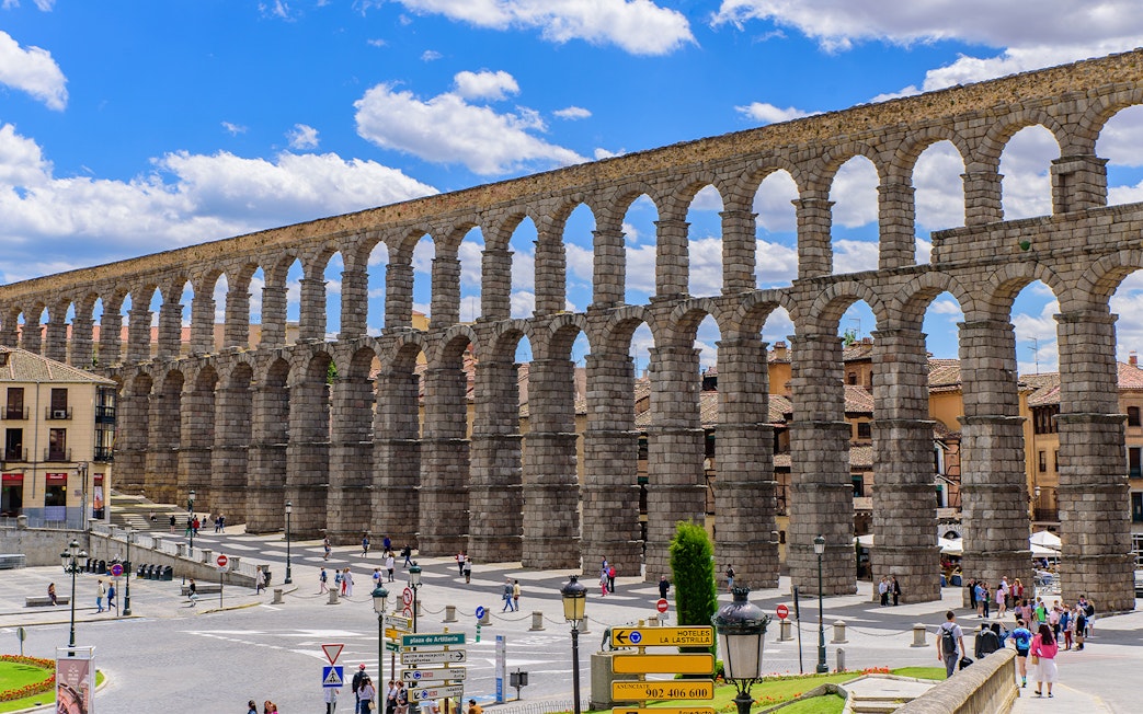 Roman aqueduct in Segovia with arches spanning a city square.