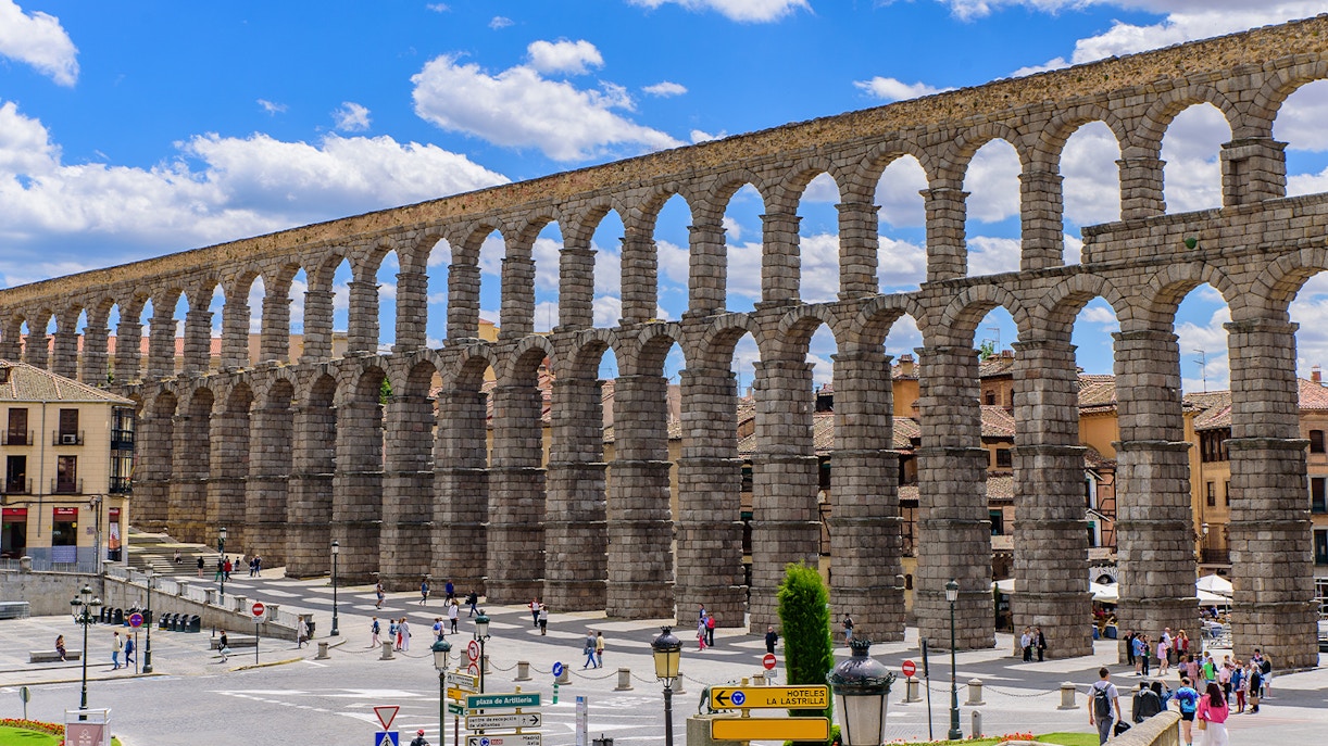 Roman aqueduct in Segovia with arches spanning a city square.