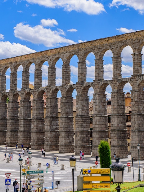 Roman aqueduct in Segovia with arches spanning a city square.