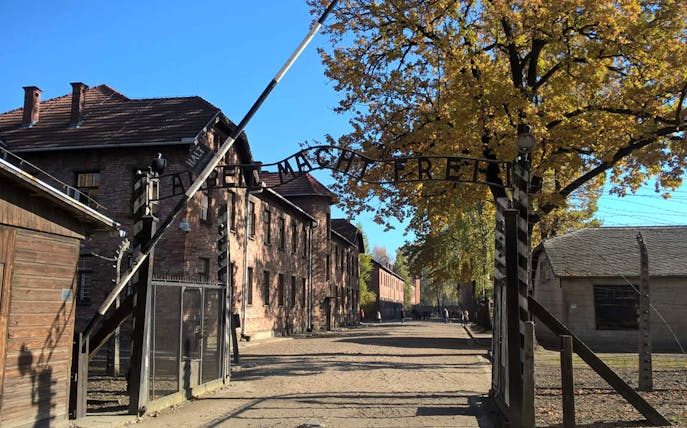 Entrance gate to Auschwitz concentration camp with "Arbeit Macht Frei" sign, part of Krakow day tour.